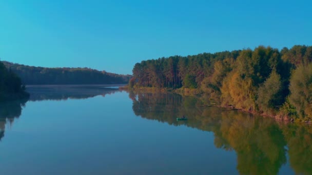 Magányos halász egy hajón. halászhajó az őszi tó közepén hajnal — Stock videók