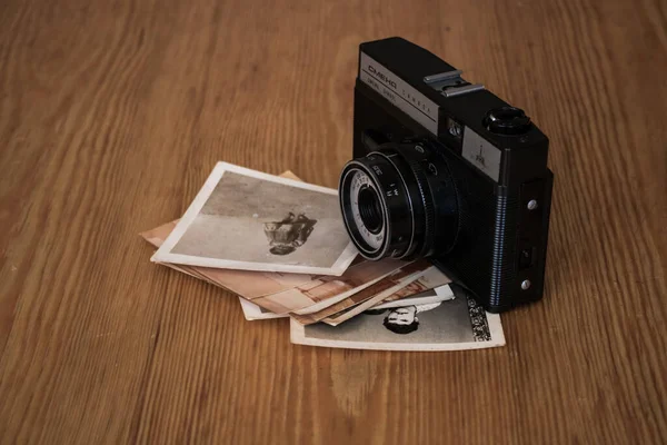 Antik kamera ve eski fotoğraflar ahşap arka planda.