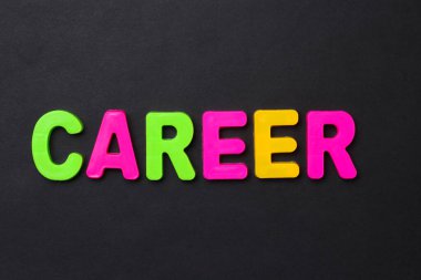 CAREER kelimesi çocukların manyetik alfabesinin harfleriyle siyah bir arkaplan üzerine yazılmış.