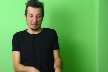 Açık yeşil arka planda etkileyici bir genç adam ya da adam. İğrenme duygusu.