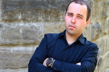 Eski bir duvarın bulanık arka planında tişörtlü genç bir adam.