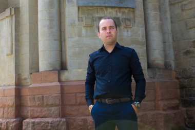 Yazı veya metin koymak için fotokopi alanı olan eski bir taş binanın arka planındaki genç adam..