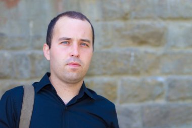Yazı veya metin koymak için fotokopi alanı olan eski bir taş binanın arka planındaki genç adam..