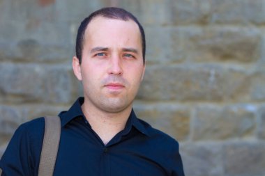 Yazı veya metin koymak için fotokopi alanı olan eski bir taş binanın arka planındaki genç adam..