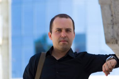 Bir yaz günü şehir ortamında bir adamın portresi. Bir gökdelenin bulanık arka planında. Yazı ya da metin yerleştirmek için fotokopi alanı var..