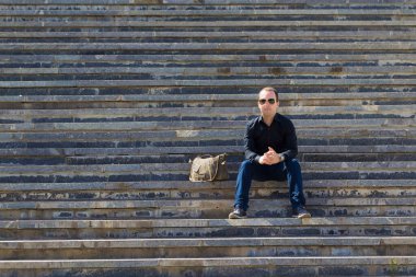 Bir yaz günü şehir ortamında bir adamın portresi basamaklarda bir yazı ya da yazı koymak için fotokopi alanı ile birlikte..