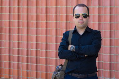 Yaz günü şehir ortamında bir adamın portresi arkaplanda kırmızı dekoratif tuğlalardan oluşan bir duvarın üzerine yazıyı ya da metni yerleştirmek için..