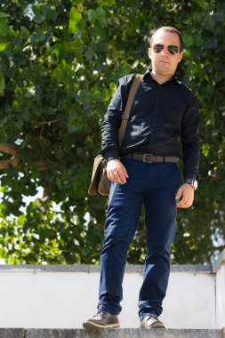 Bir yaz günü şehir ortamında bir adamın portresi merdivenlerin basamaklarında bir yazıt veya metin yerleştirmek için bir kopya alanı ile.