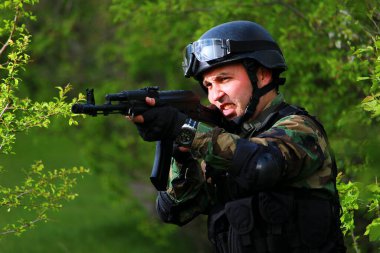 Ormandaki özel kuvvetlerden bir asker tüfeğiyle rakiplerine saldırıyor..