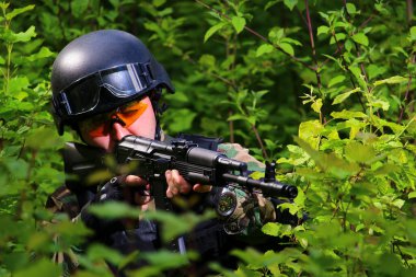 Ormandaki yeşil ağaçların dallarına gizlenmiş özel kuvvetler askerleri vuruyor.