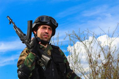 Doğası mavi gökyüzü ve yeşilliği olan çok güzel bir manzaranın arka planında dik bir savaşçı.