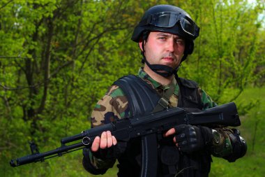 Kasklı ve silahlı bir paraşütçü. Aydınlık bir yaz gününde portre