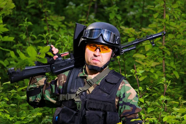 A man with a rifle on the shoulders of airsoft glasses.