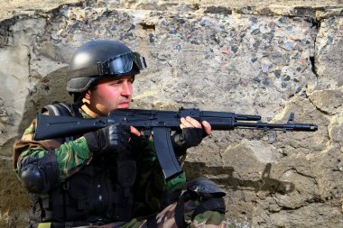 Güneşli bir günde çölde beton bir duvarın arkasında tüfeği olan bir asker. Yaşam biçimi