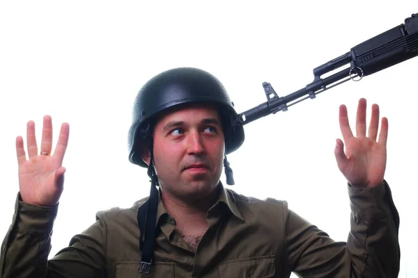 A man in a military helmet with arms raised at gunpoint surrenders on a white background