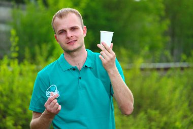 Marrs 'ın yeşil tişörtlü bir adam elinde buruşmuş plastik bir bardak tutuyor ve doğru seçim için kağıt bardak kaldırıyor..
