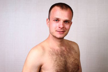 Evde çıplak gövdeli bir adam duvarın karşısında bir odada.