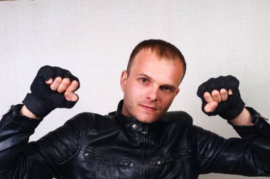 Siyah deri ceketli ve mühürlü mutlu genç motorcu. Kavganın alegorisi ve ellerin direksiyonda olması, motor hırıltısı ve saldırganlık.