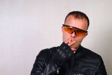 Siyah deri ceketli, gözlüklü, sigara içen mutlu, genç motorcu. Duygusal Numaralar