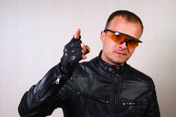 Happy handsome young biker in black leather jacket and sport glasses. Challenge Emotion