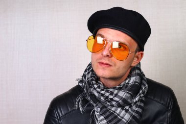 Deri ceketli bir adam, motosikletli, arka plandaki bulanık duvarda sallanan bir adam.