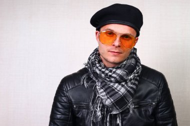 Deri ceketli bir adam, motosikletli, arka plandaki bulanık duvarda sallanan bir adam.