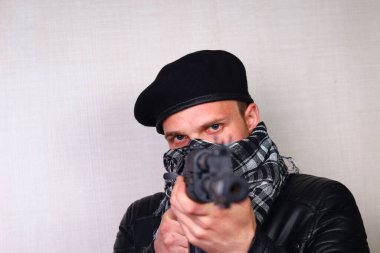 Siyah deri ceketli, saldırı tüfekli genç adam.