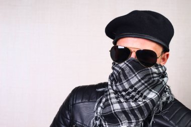 Deri ceketli bir adam, motosikletli, arka plandaki bulanık duvarda sallanan bir adam.