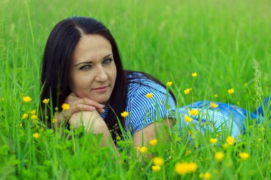 Güzel genç esmer bir yaz gününde doğanın, yeşilliğin ve çiçeklerin tadını çıkarıyor.