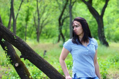 Güzel, genç bir esmer şehirde dinleniyor. Ağaçların arasına park et.