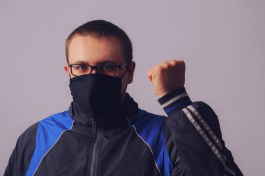 Yüzünde siyah maske ve gözlüklü bir adam duvara yaslanmış, kaslı. Salgın covid-19 (koronavirüs enfeksiyonu) konsepti. İyileşme duygusu.