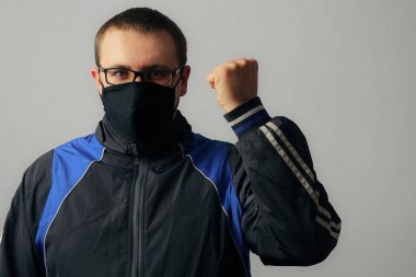 Yüzünde siyah maske ve gözlüklü bir adam duvara yaslanmış, kaslı. Salgın covid-19 (koronavirüs enfeksiyonu) konsepti. Başarı duygusu