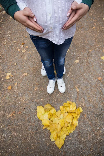 Yellow leaves in the shape of a heart and legs, abstract background of love relationships