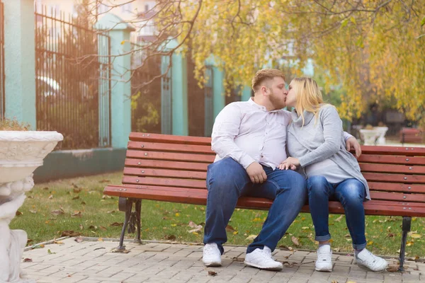 快乐的丈夫和怀孕的妻子在公园的长椅上亲吻着 — 图库照片