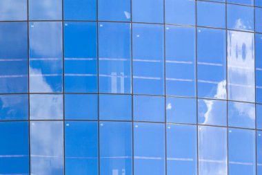 Gökyüzünün güzel bir yansıması ve arka planı olan çok katlı bir binanın cam cephesi.