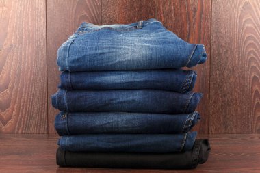 Güzel ahşap bir arka planda kot pantolon yığını