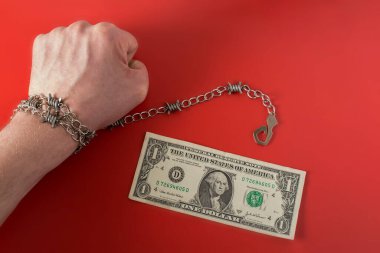 Kancalı dikenli telle sarılmış ve kırmızı arka planda bir dolar.