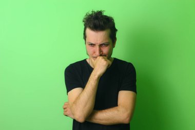 Açık yeşil arka planda etkileyici bir genç adam ya da adam. Derin düşüncenin duygusu