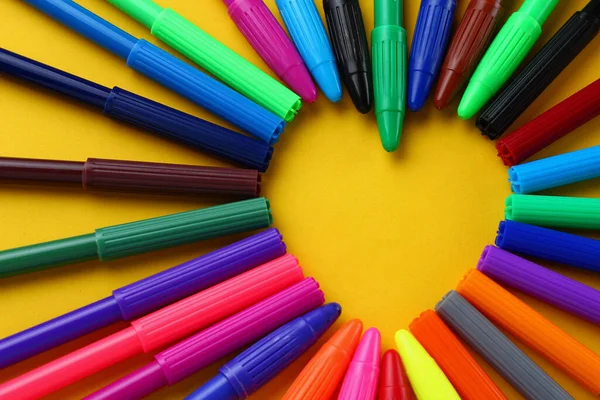 Felt pens of different colors form a heart-shaped frame for text or lettering. Background with copyspace for inscription