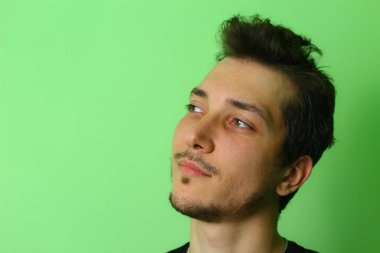 Açık yeşil arka planda etkileyici bir genç adam ya da adam. Derin düşüncenin duygusu