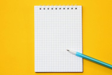 Damalı bir defter ve bir kalem boş bir sayfa. Yazı ya da metin için bir yer. Kopyalama alanı olan bir model. Sarı arkaplan
