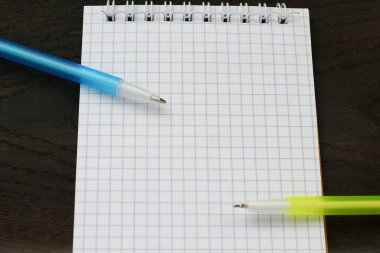 Boş defter ve iki kalem aç. Kopyalama alanı olan bir model. Ahşap arka. Başlığa seçici odaklanma