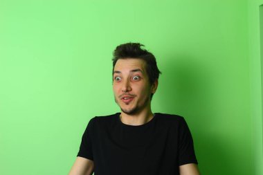 Açık yeşil arka planda etkileyici bir genç adam ya da adam. Samimi şaşkınlık duygusu