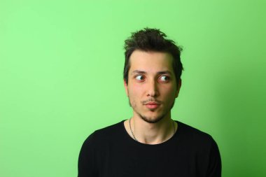 Açık yeşil arka planda etkileyici bir genç adam ya da adam. Yeni bir fikirle ilham geldi..