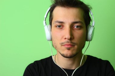 Açık yeşil arka planda etkileyici bir genç adam ya da adam. Ciddi ve işe odaklanmış.