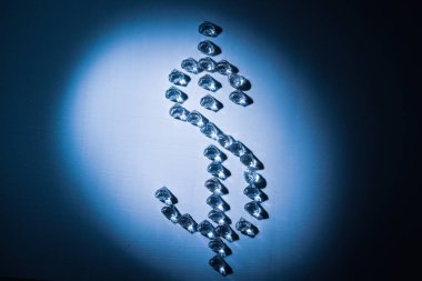 Taştan yapılmış dolar sembolü. Kesiğin şekli bir elmasa benziyor. Kuvvetli zıt ışık ve vignet etkisi. Arkaplan