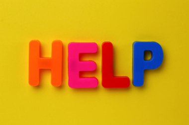 Çok renkli manyetik harflerle yazılmış bir metin. Yardım edin. Sarı arkaplan