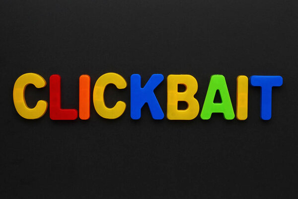 Text made in multicolored magnetic letters. CLICKBAIT. Black background