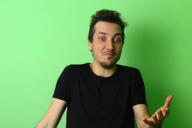 Açık yeşil arka planda etkileyici bir genç adam ya da adam. Samimi şaşkınlık duygusu