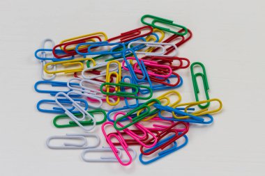 Birçok renkli ataç beyaz ahşap bir masanın üzerinde yatıyor. Arkaplan